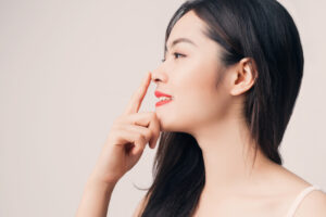 Smiling woman, seen in side profile, touches her nose before NasalTox™