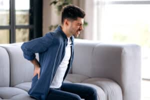 A man with chronic pain holding his lower back